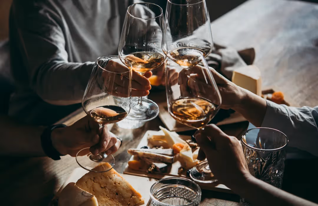 An intimate wine and cheese tasting experience with friends clinking glasses over a beautifully arranged cheese board. A refined HOMETAINMENT experience in London, perfect for private wine pairings, luxury dining, and exclusive home gatherings.