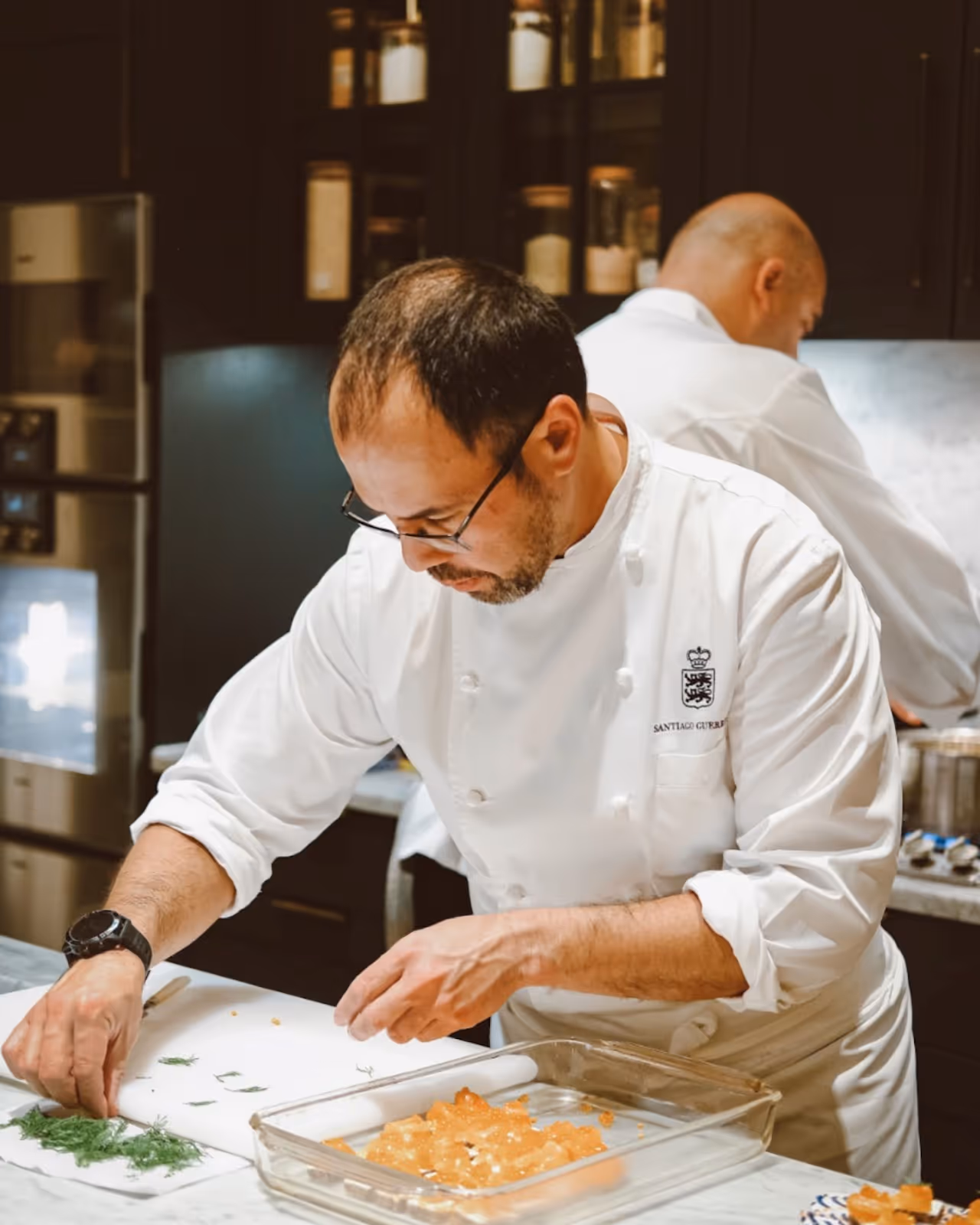 A working luxury private chef in a nice kitchen in London carefully placing fresh dill on to smoke salmon starters.