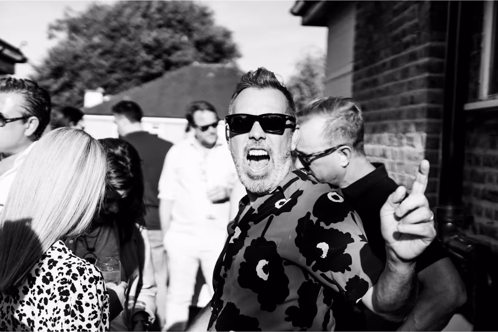 A man who is happily singing along to music at a rooftop party in London.