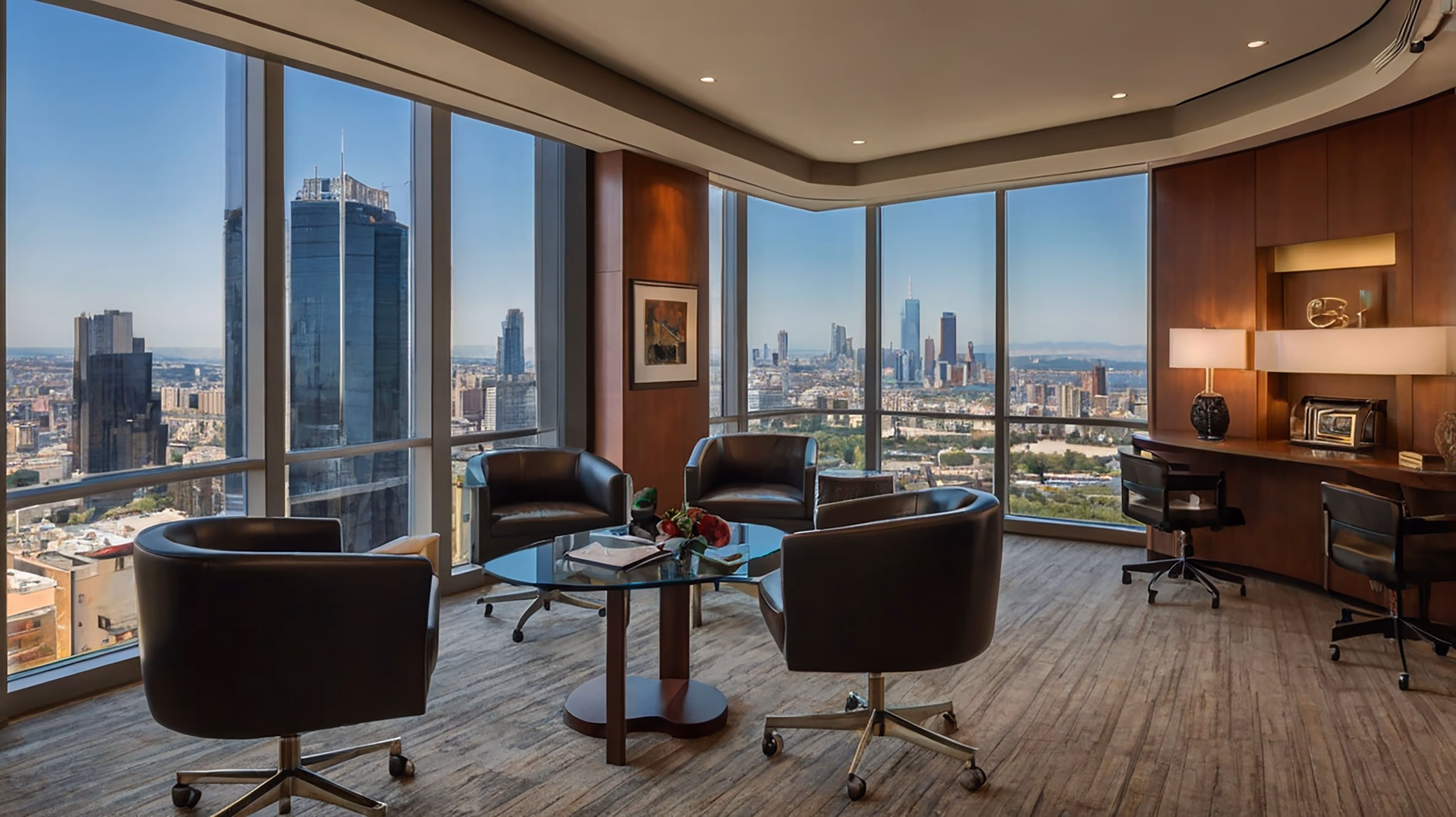 Modern office lounge with black swivel chairs around a glass coffee table and large windows showing a cityscape.