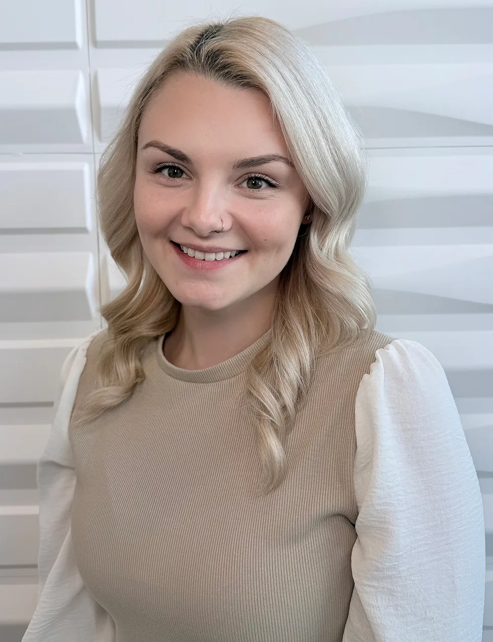 A profile picture of Stephanie Harris in front of a white wall with a raised wave pattern.