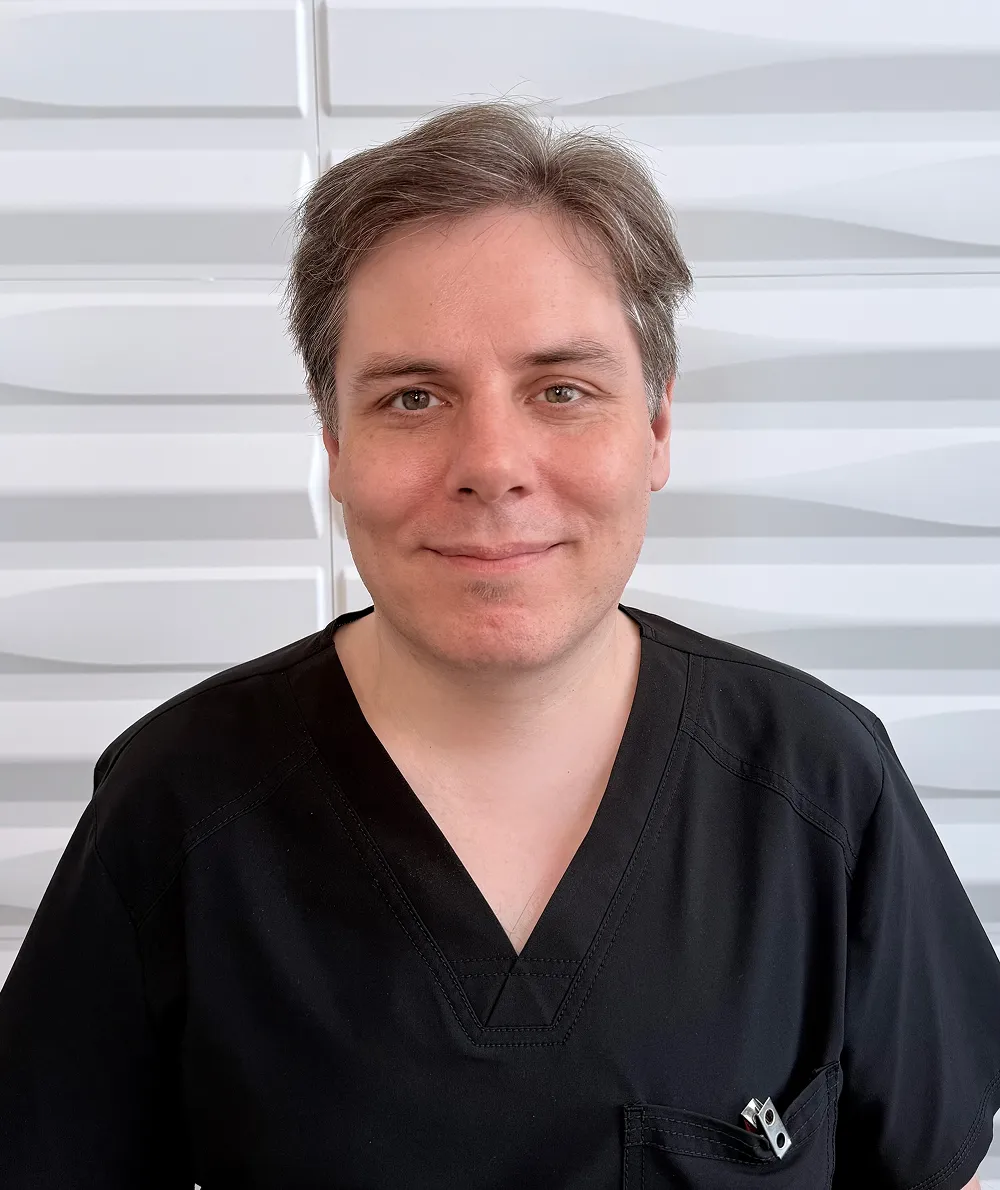 A profile picture of Chris DeVries in front of a white wall with a raised wave pattern.