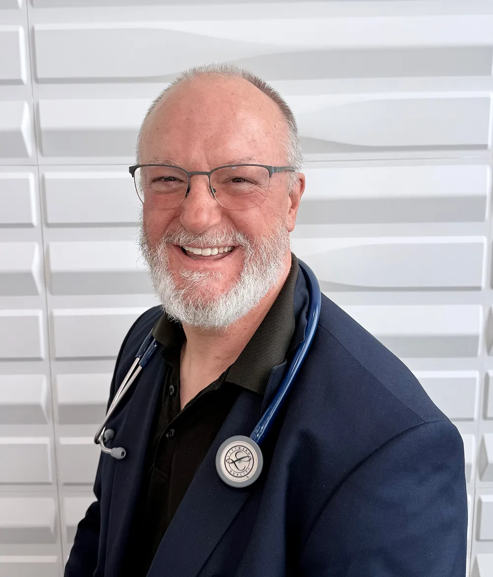 A profile picture of Dr. Richard Rusk in front of a white wall with a raised wave pattern.