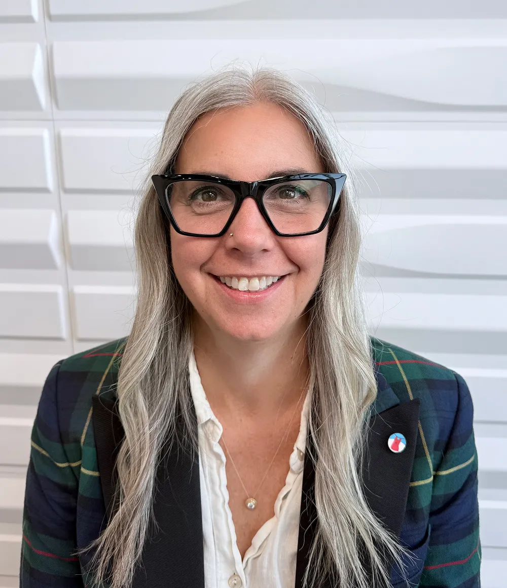 A profile picture of Dr. Heather Ring in front of a white wall with a raised wave pattern.
