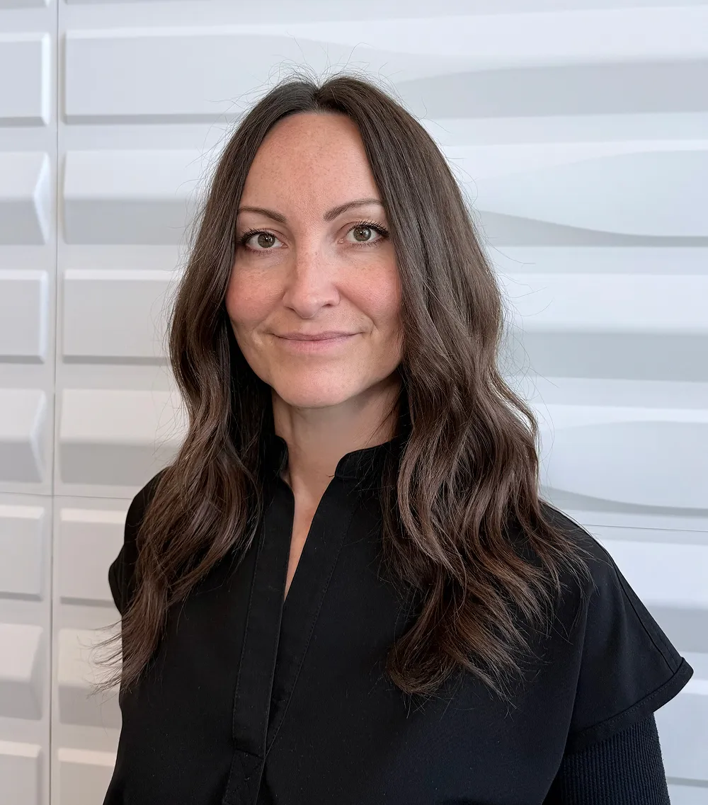 A profile picture of Christine Briscoe in front of a white wall with a raised wave pattern.