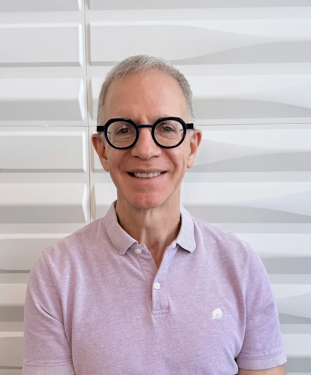A profile picture of Dr. Hillel Sommer in front of a white wall with a raised wave pattern.