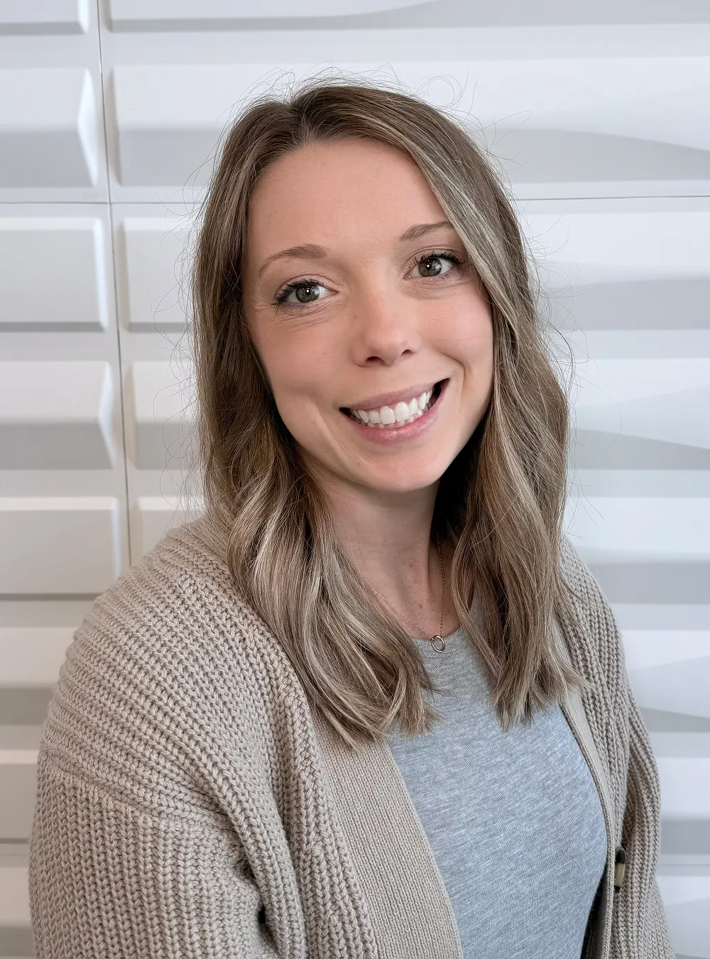 A profile picture of Dixie Aguair in front of a white wall with a raised wave pattern.