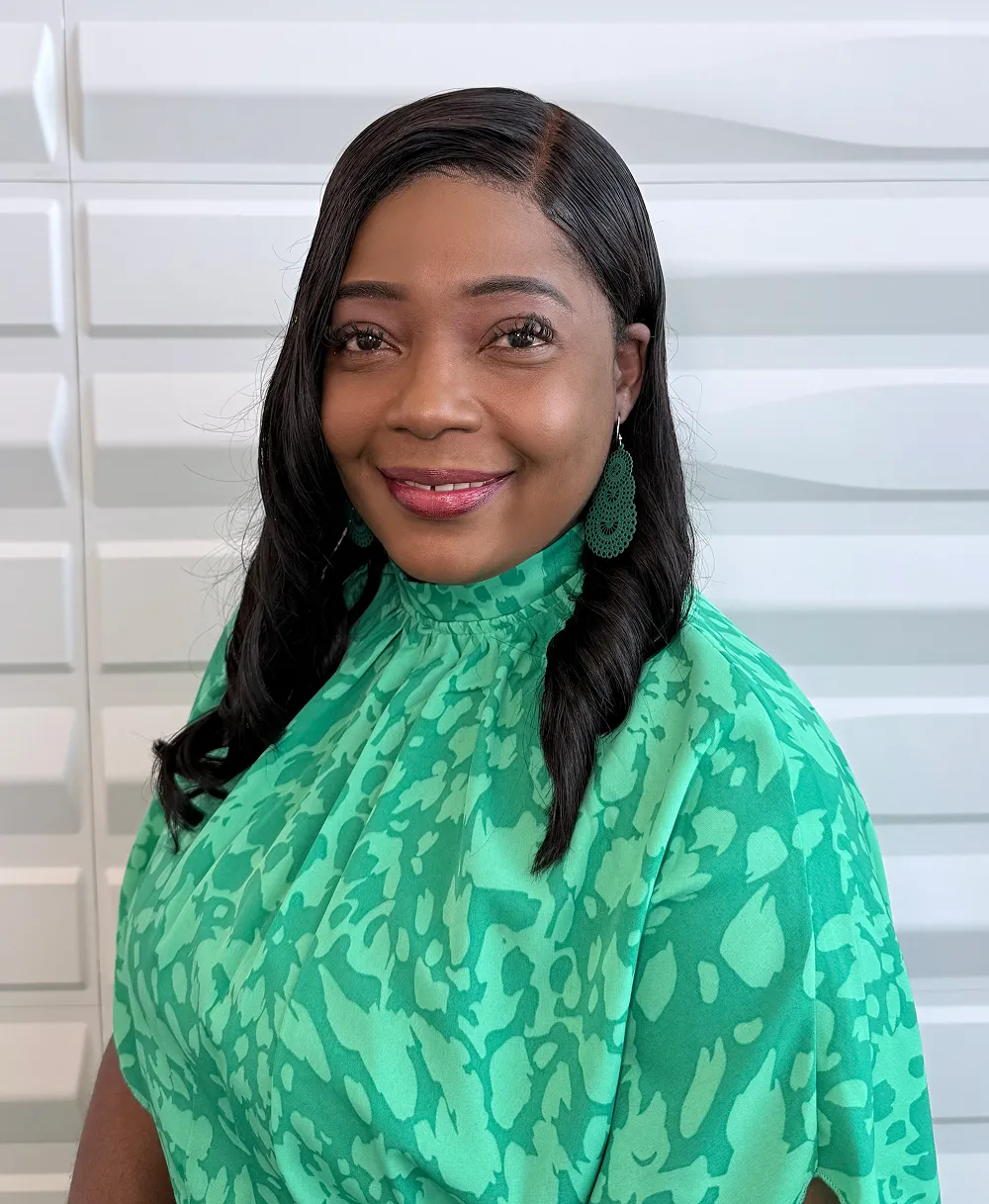 A profile picture of Tameca Brown-Hylton in front of a white wall with a raised wave pattern.