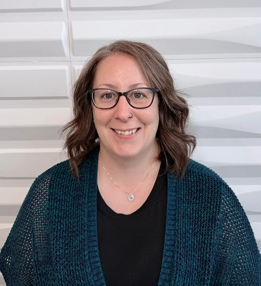 A profile picture of Meghan Couzens in front of a white wall with a raised wave pattern.