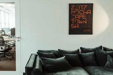 Waiting room with black sofa and frame on a wall.