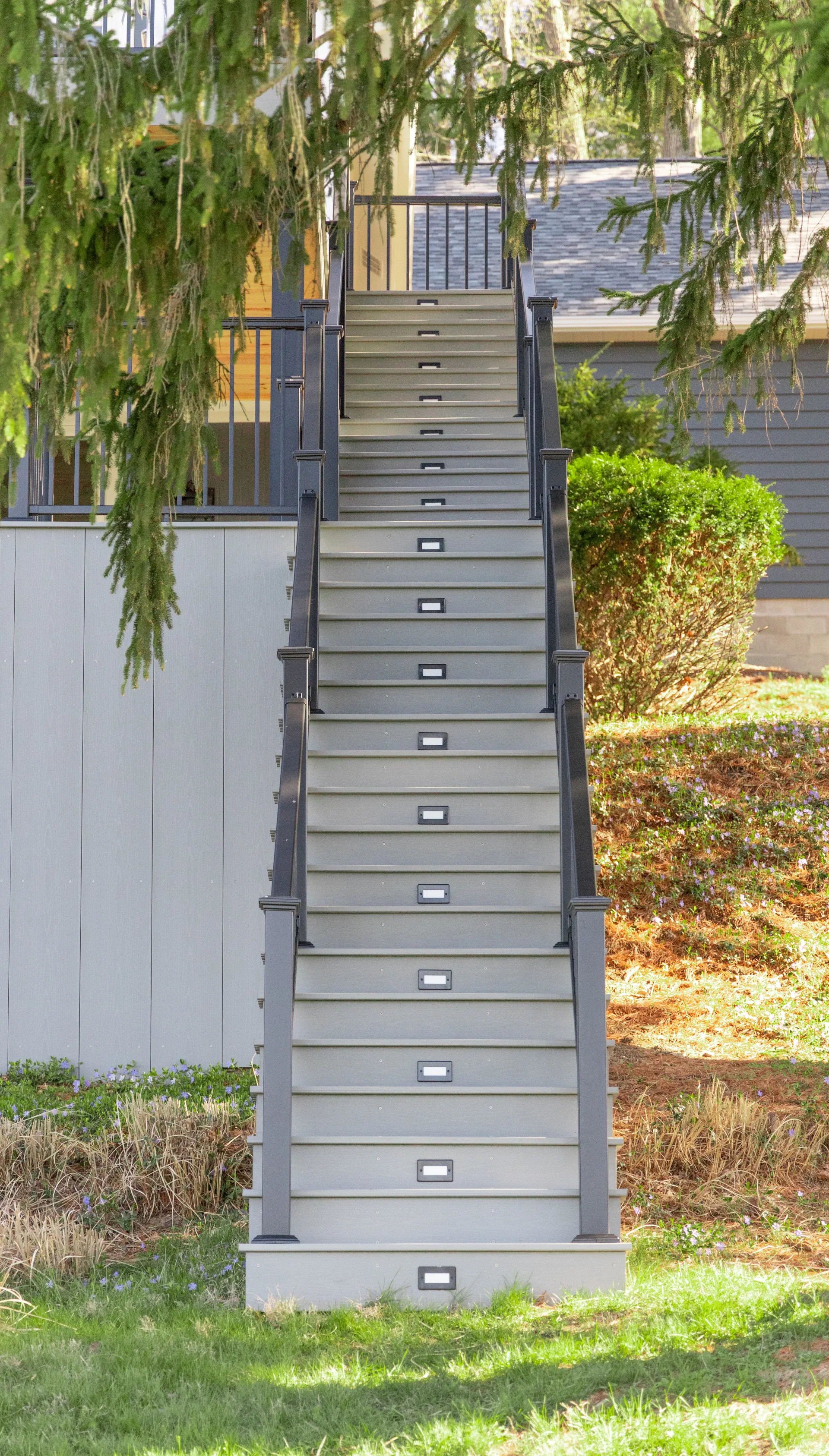 grey wood staircase with black railings and stair lights
