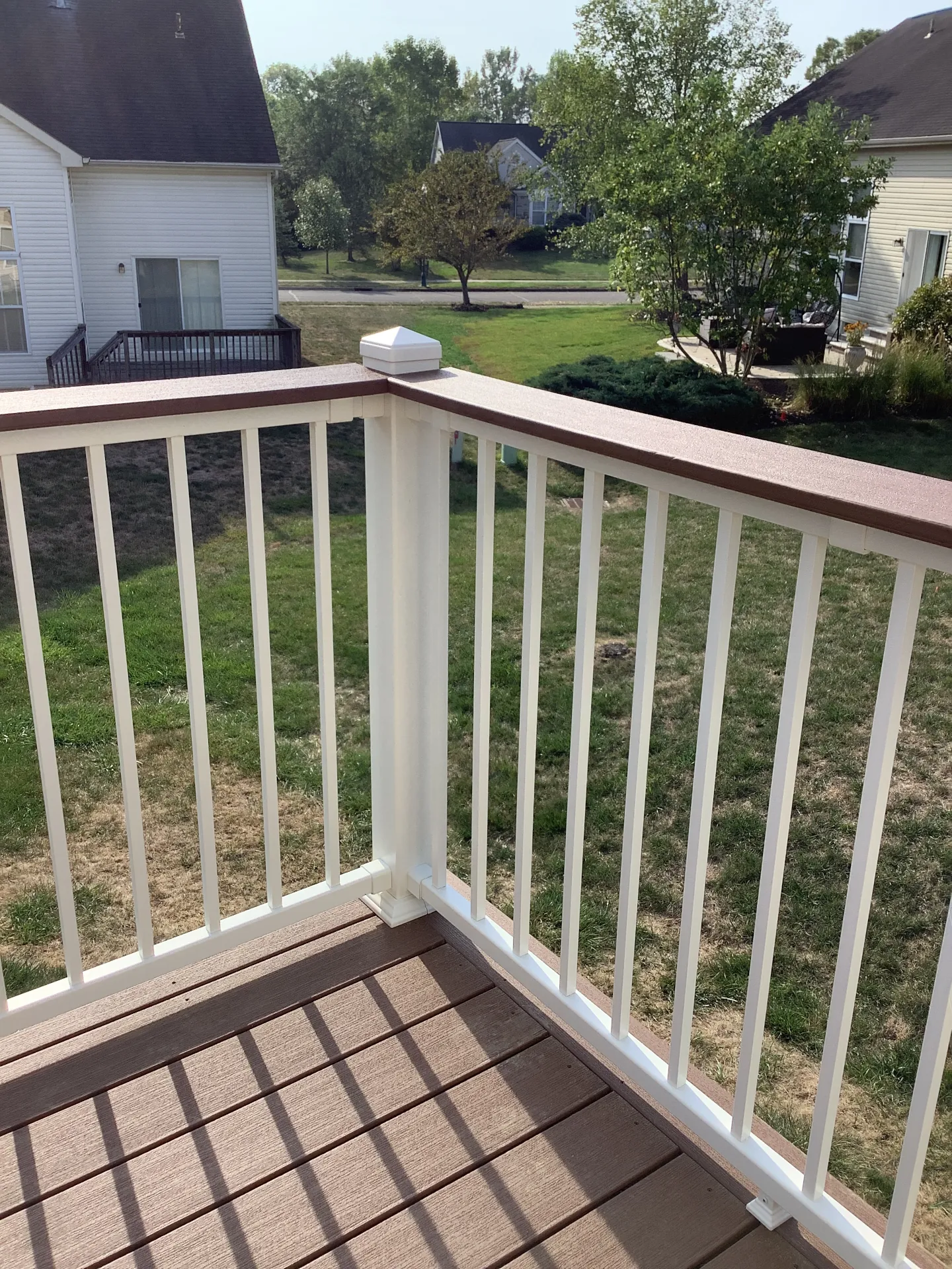 White composite deck railing with brown top rail installed on a low-maintenance composite deck in Ohio.