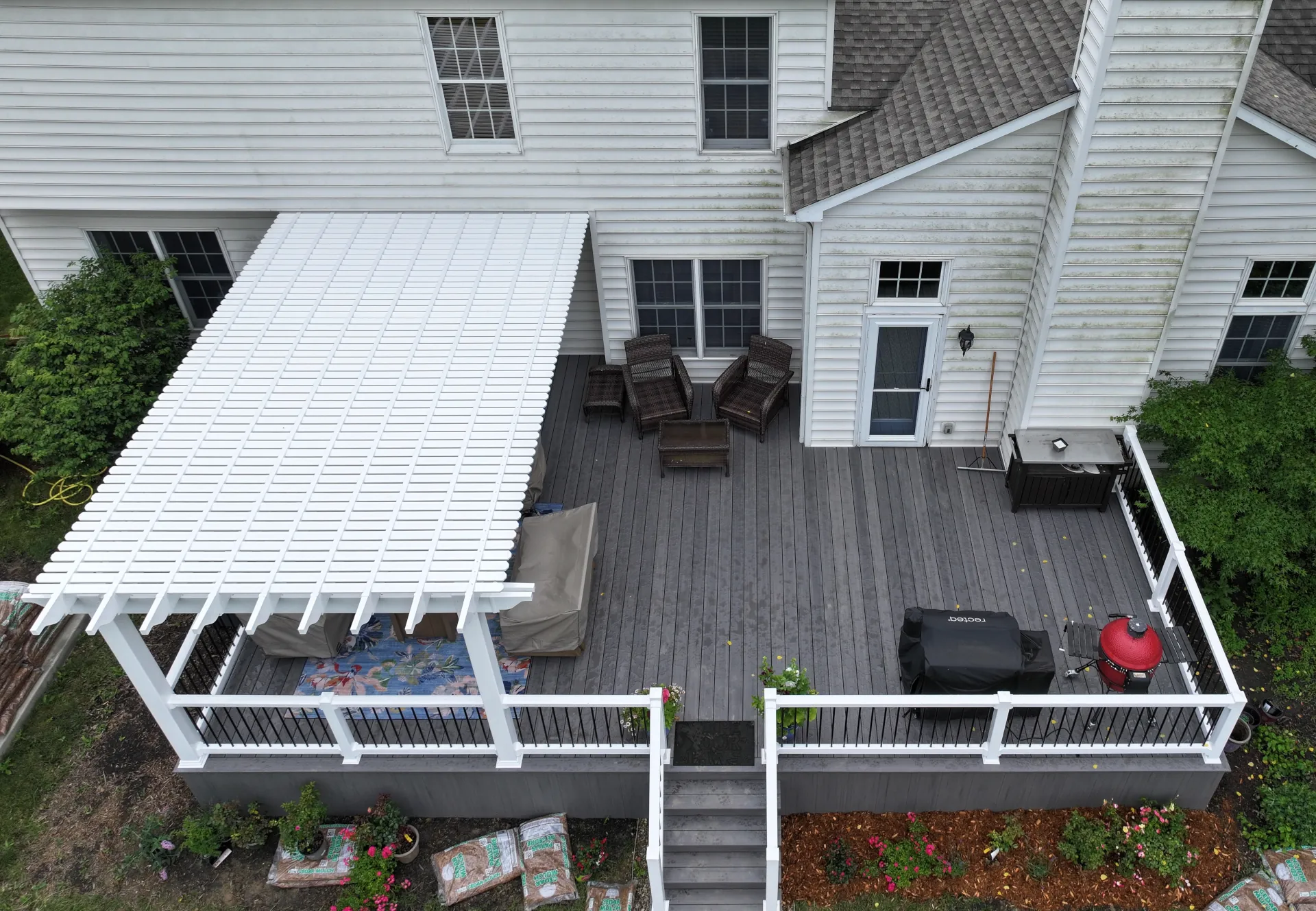 Finished composite deck with white vinyl pergola and white railing with black aluminum spindles in Powell, Ohio.