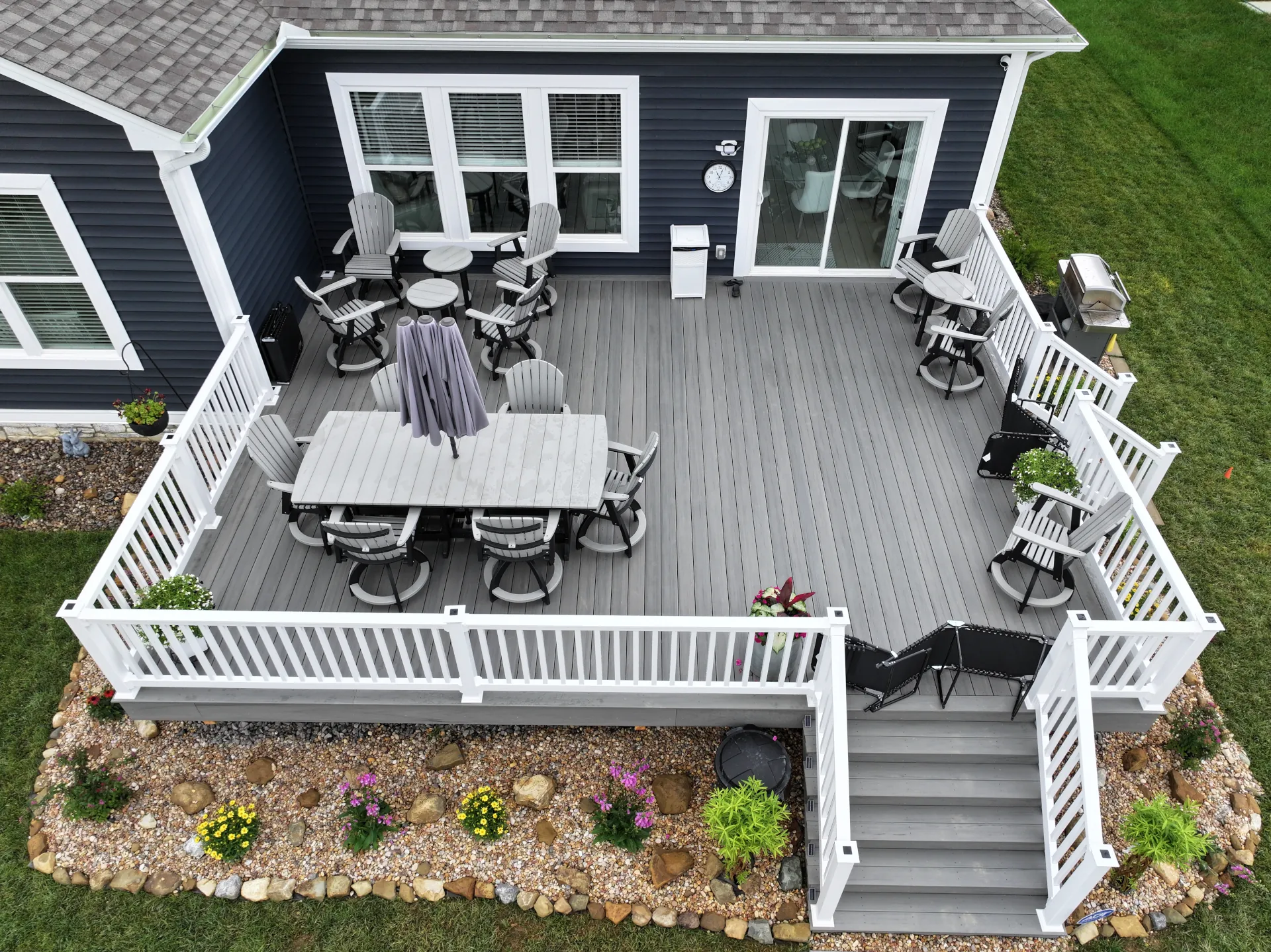 Aerial view of a large composite deck with white vinyl railing, wide stairs, and outdoor seating in Pataskala, Ohio.