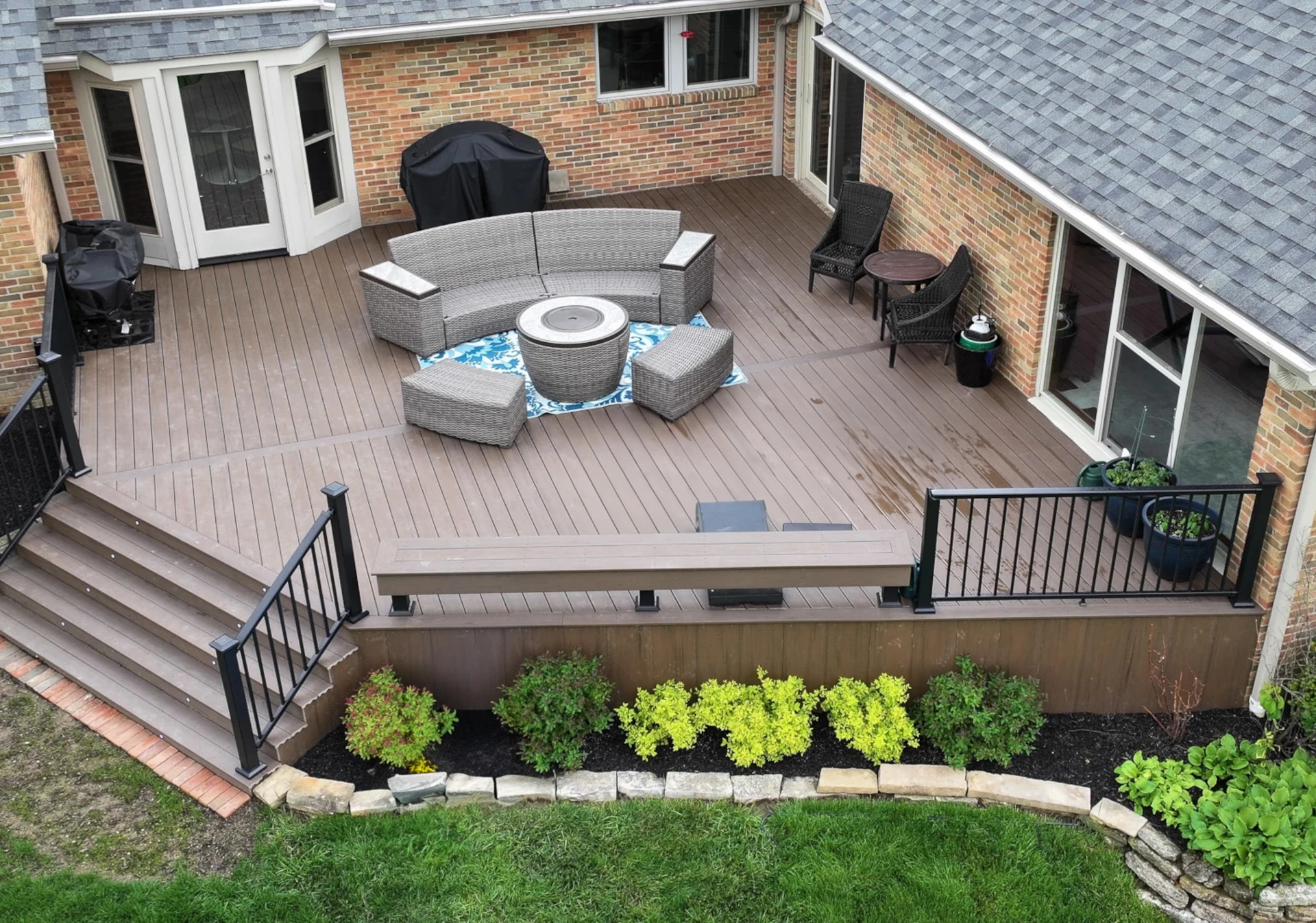 Aerial view of a spacious Dark Cocoa composite deck with black aluminum railing, built-in bench, and wide staircase in Dublin, Ohio.