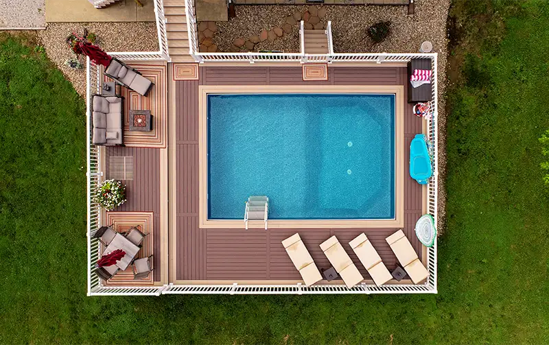 Top-down view of a custom two-tone composite pool deck with decorative inlays and white vinyl railing in Sardis, Ohio.