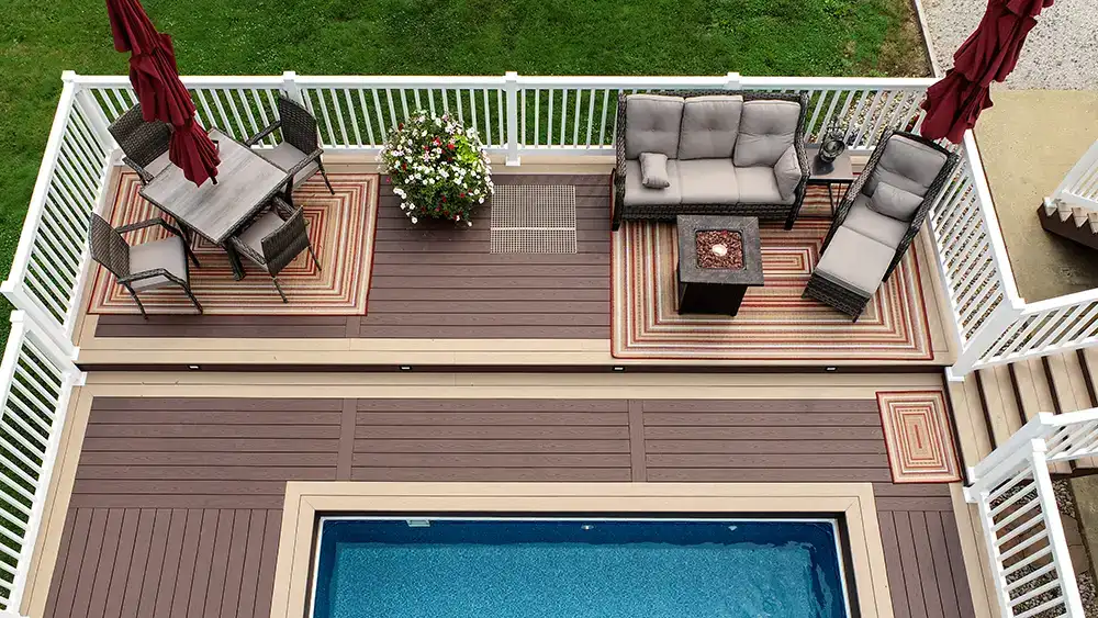 Brownstone and Kona composite pool deck with custom inlays, white vinyl railing, and outdoor seating areas in Sardis, Ohio.