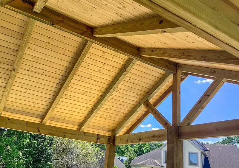 Exposed timber framing and wood ceiling beneath a custom gable-roof covered porch in Grove City, Ohio.