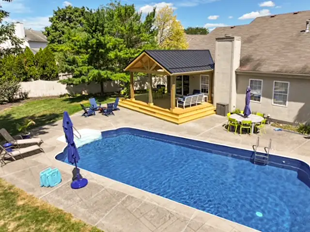 Backyard pool with a custom pressure-treated covered porch and black metal gable roof in Grove City, Ohio.