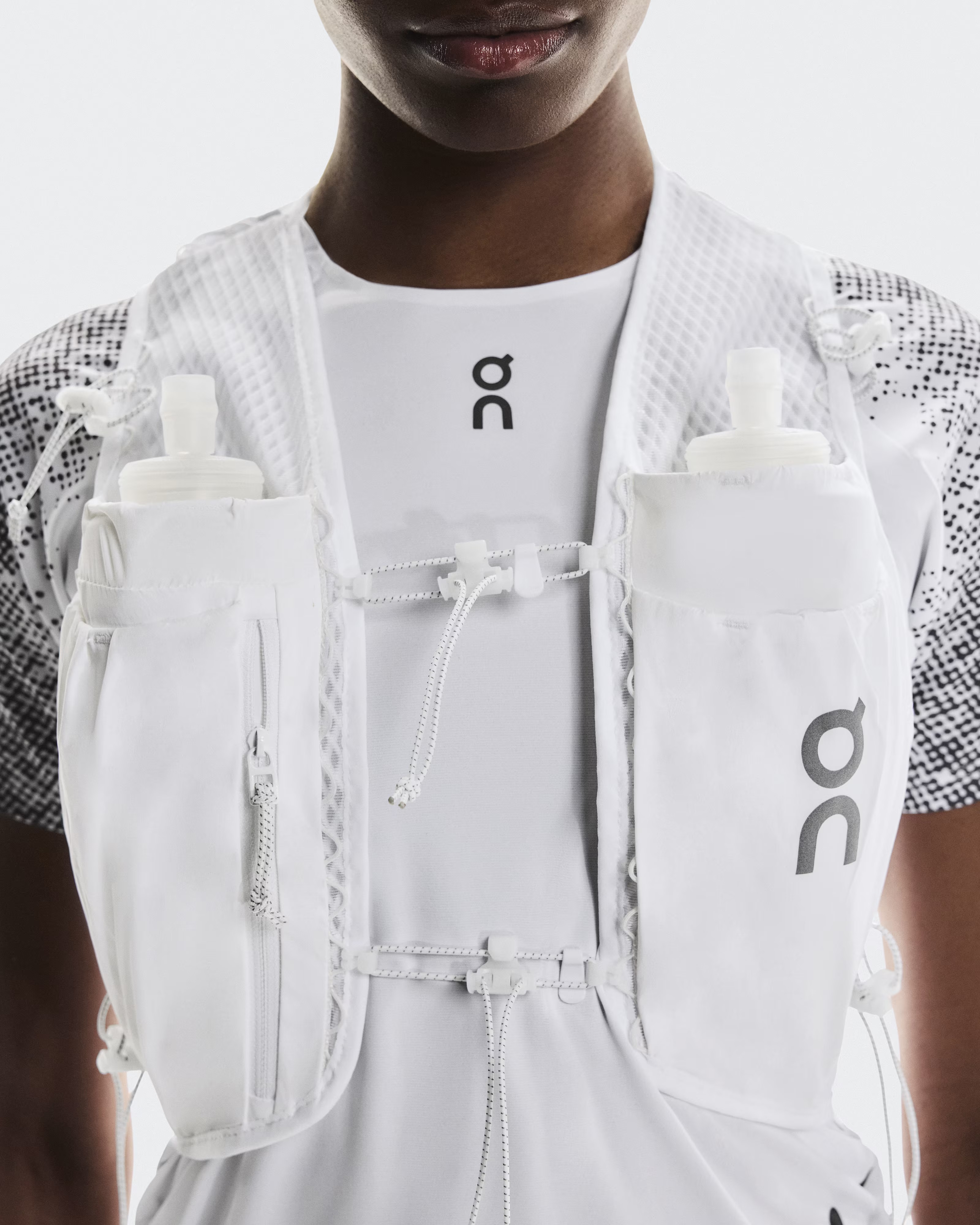 Close up of On Ultra Vest Pro in wite showing storage compartments, zip features and front fastener up close