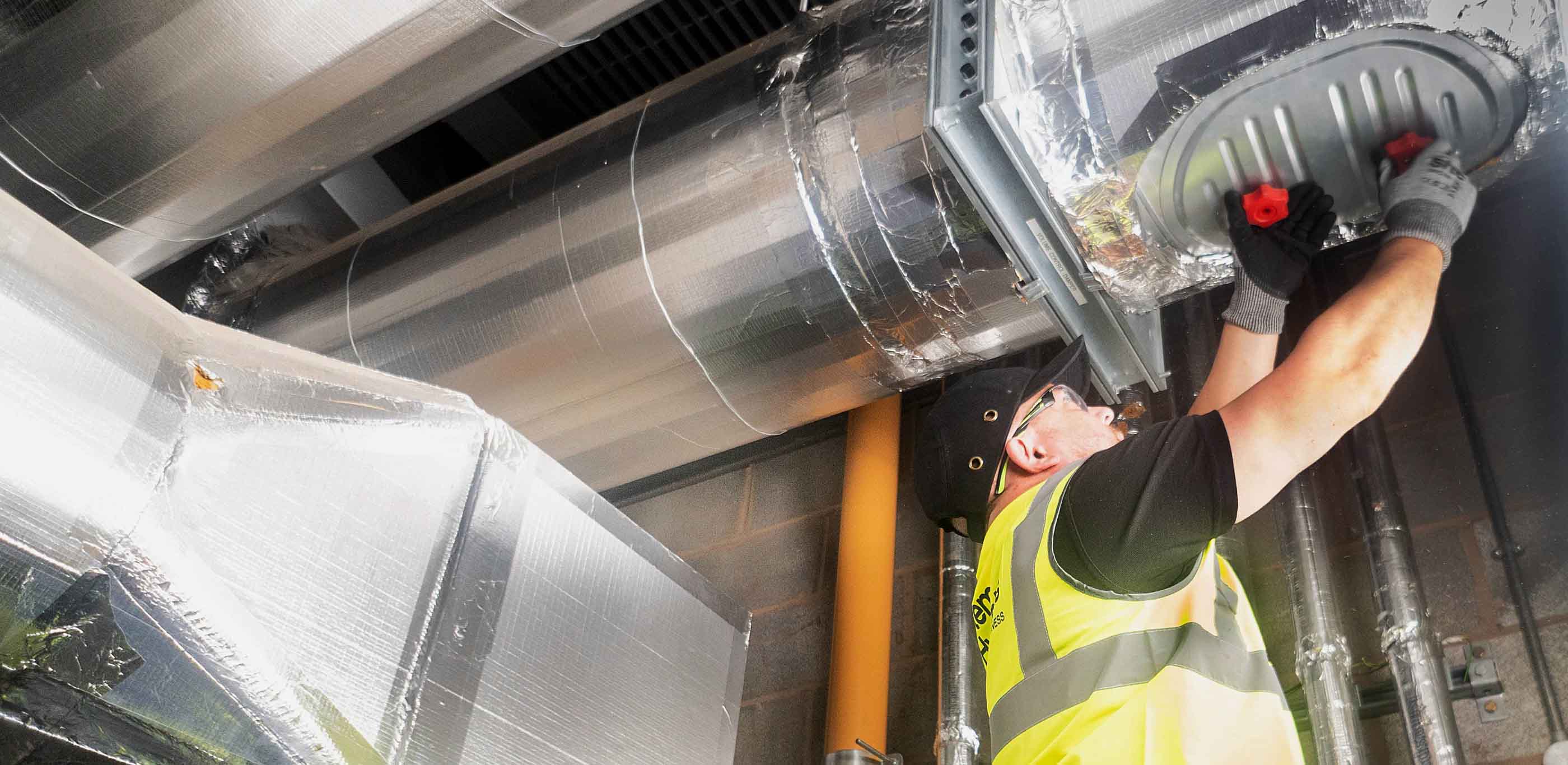 Man in high-viz and hat replacing a fire damper cover 