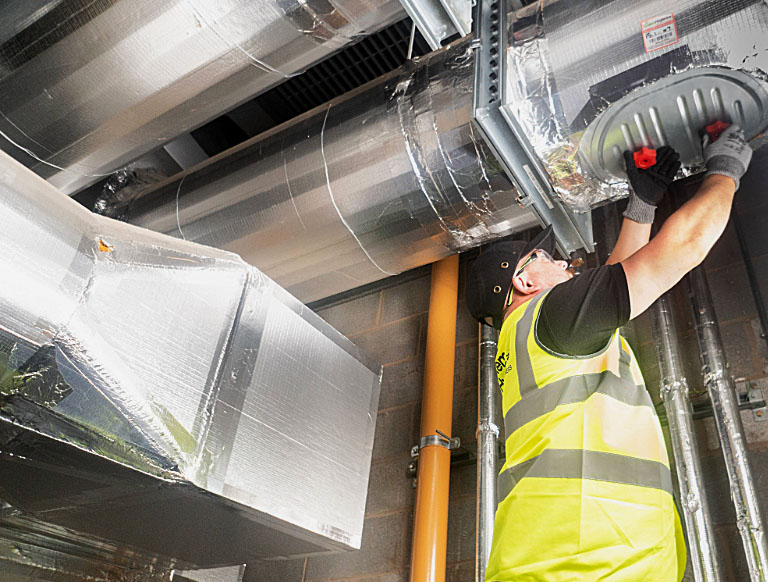 Man in high-viz and hat replacing a fire damper cover 
