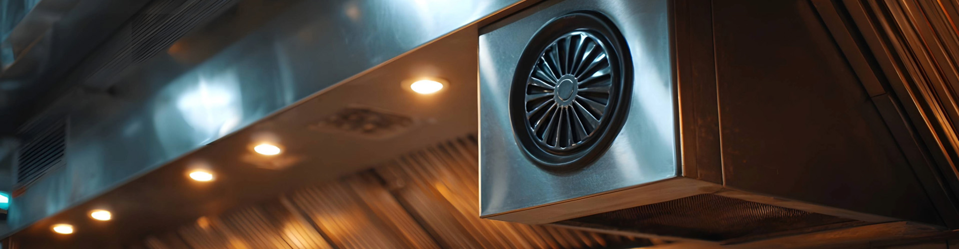 Commercial kitchen extract system with stainless steel ventilation hood and fan in restaurant.