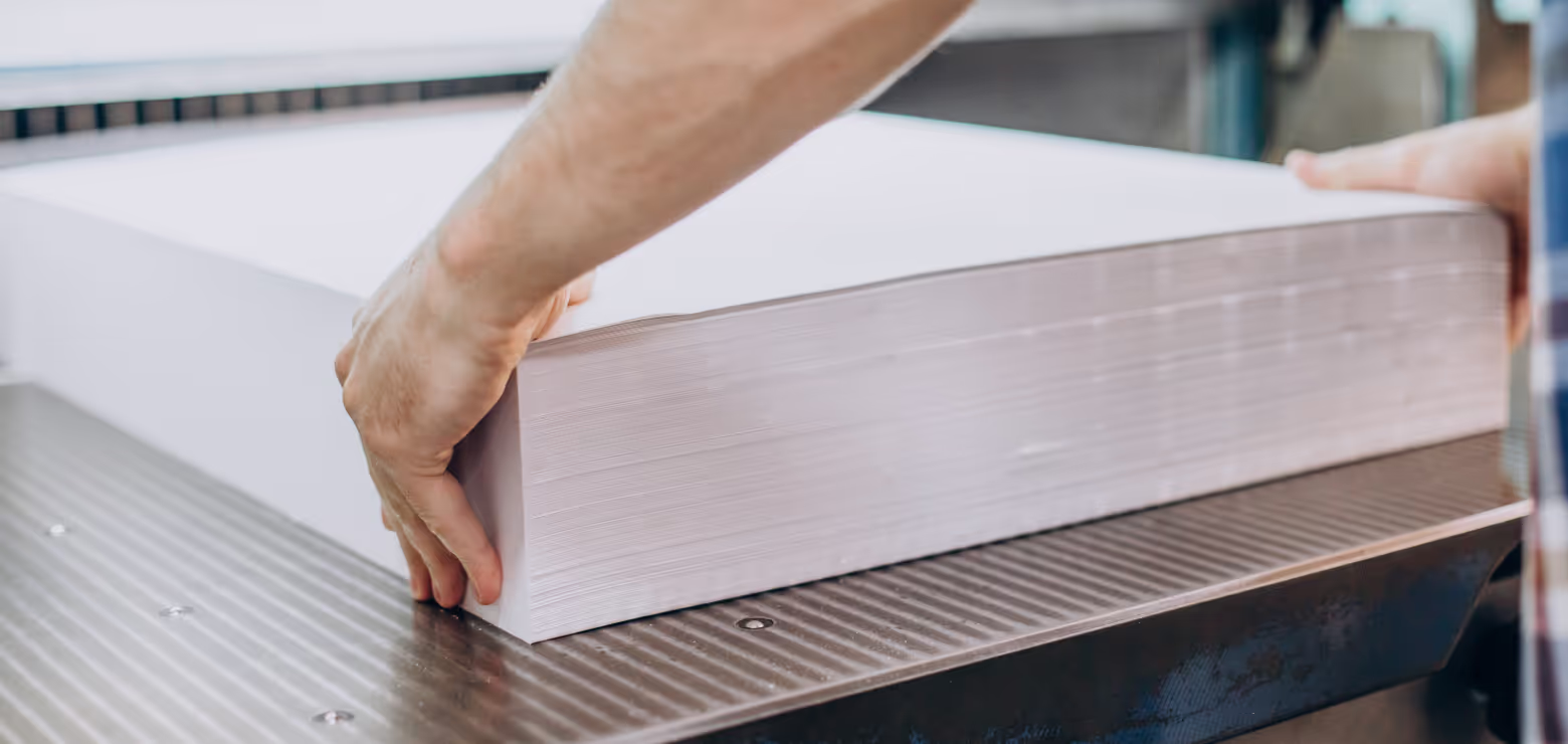 Ein Stapel Papier wird in eine Schneidemaschine eingelegt