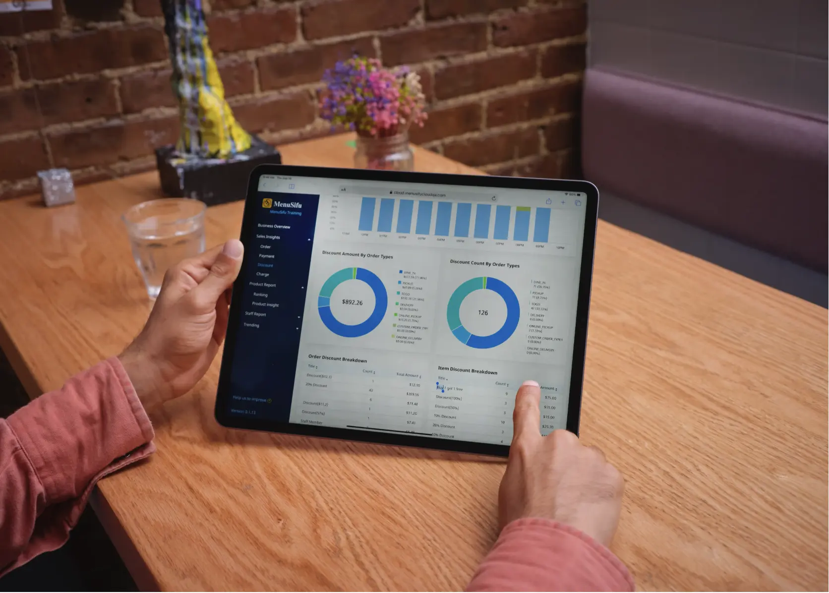 A restaurant owner reviewing real-time sales and performance analytics on the MenuSifu cloud dashboard displayed on a tablet device.