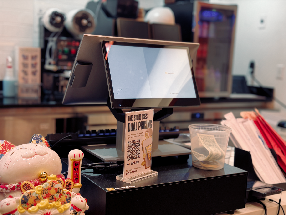 餐饮门店柜台展示MenuSifu餐饮POS系统设备,屏幕显示双重定价信息与品牌标识,体现现代餐饮数字化管理与透明收费。