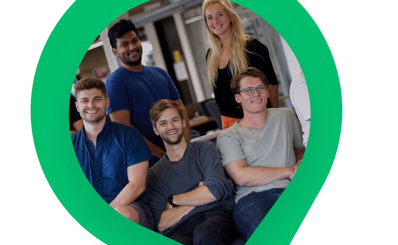 Group of five young adults smiling and posing indoors with a large green circular shape framing them.