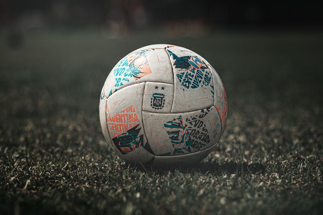Close-up of a soccer ball resting on an outdoor playing surface.