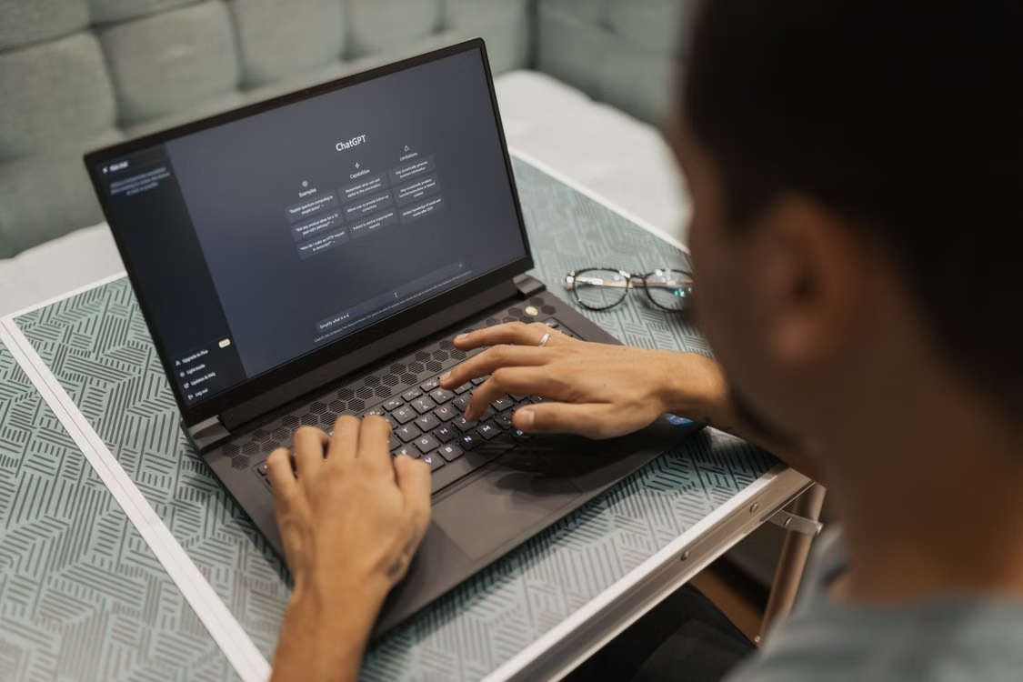 User interacting with ChatGPT on a laptop in a modern home office.