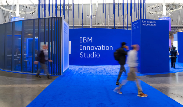 Entrance to the IBM Innovation Studio at a technology conference, featuring IBM branding and visitors walking through the exhibit.