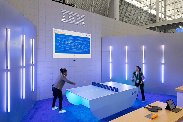 Visitors playing table tennis at an IBM technology exhibition booth featuring interactive experiences and IBM branding.