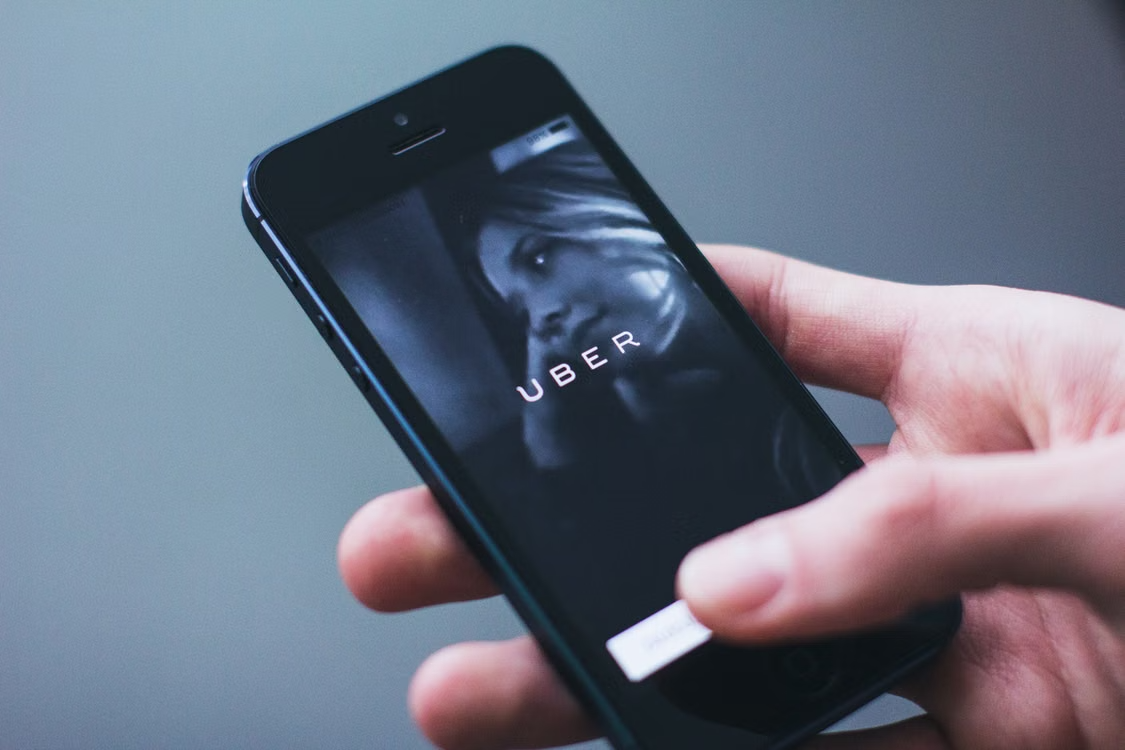 Hand holding a smartphone displaying the Uber app splash screen.