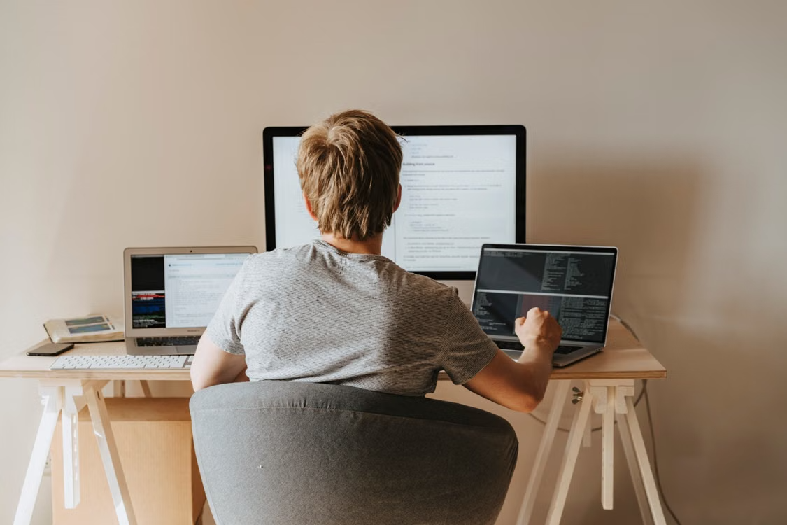 Software developer working across multiple computer screens, representing the development and testing of AI agents with LangChain.