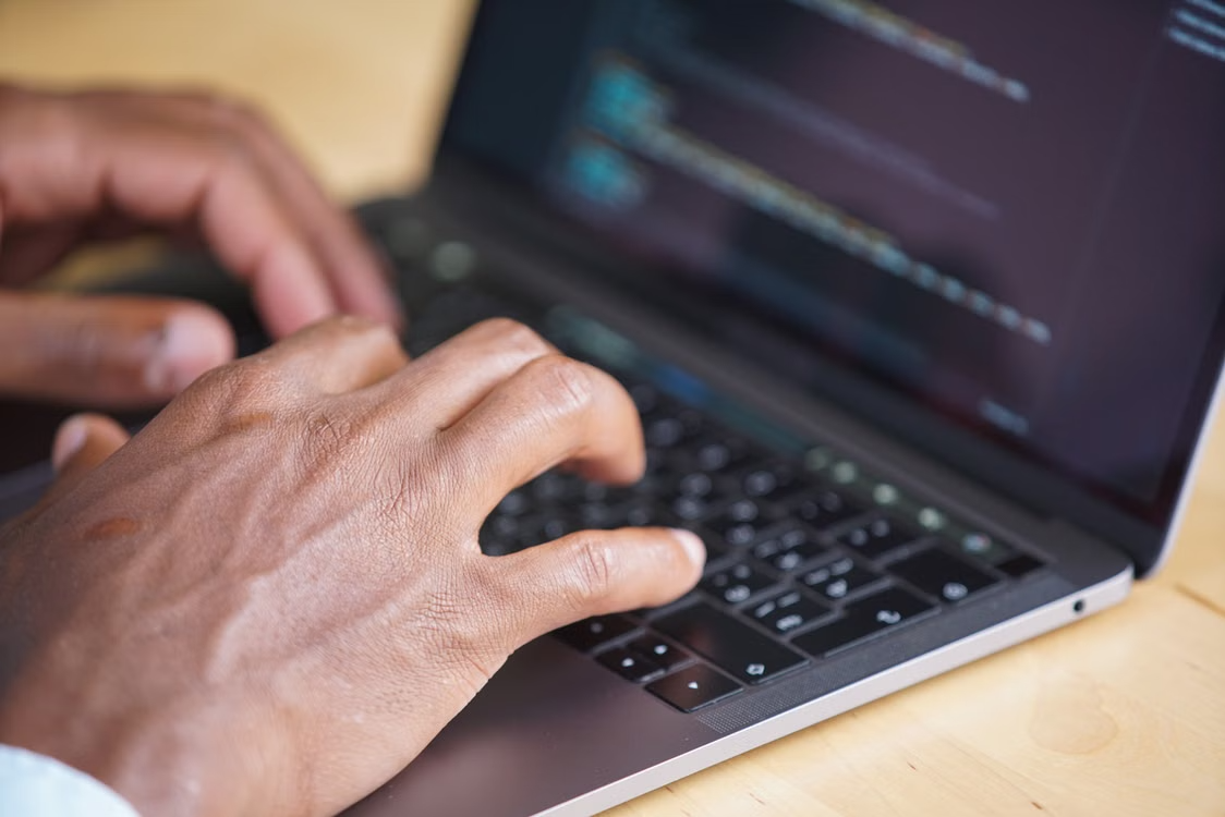 Software developer typing code on a laptop for a custom software development project.