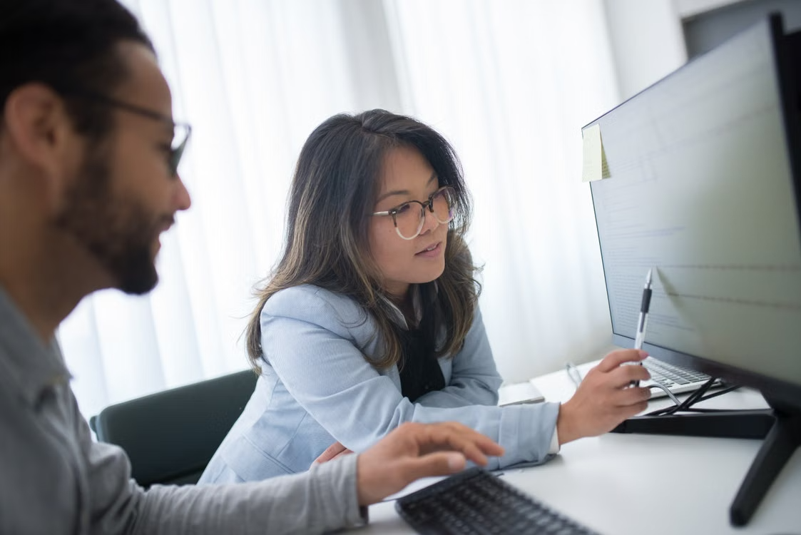 Technology leaders reviewing data on a desktop monitor, illustrating enterprise AI model evaluation based on real-world performance, reliability, cost, and business needs rather than benchmark rankings.