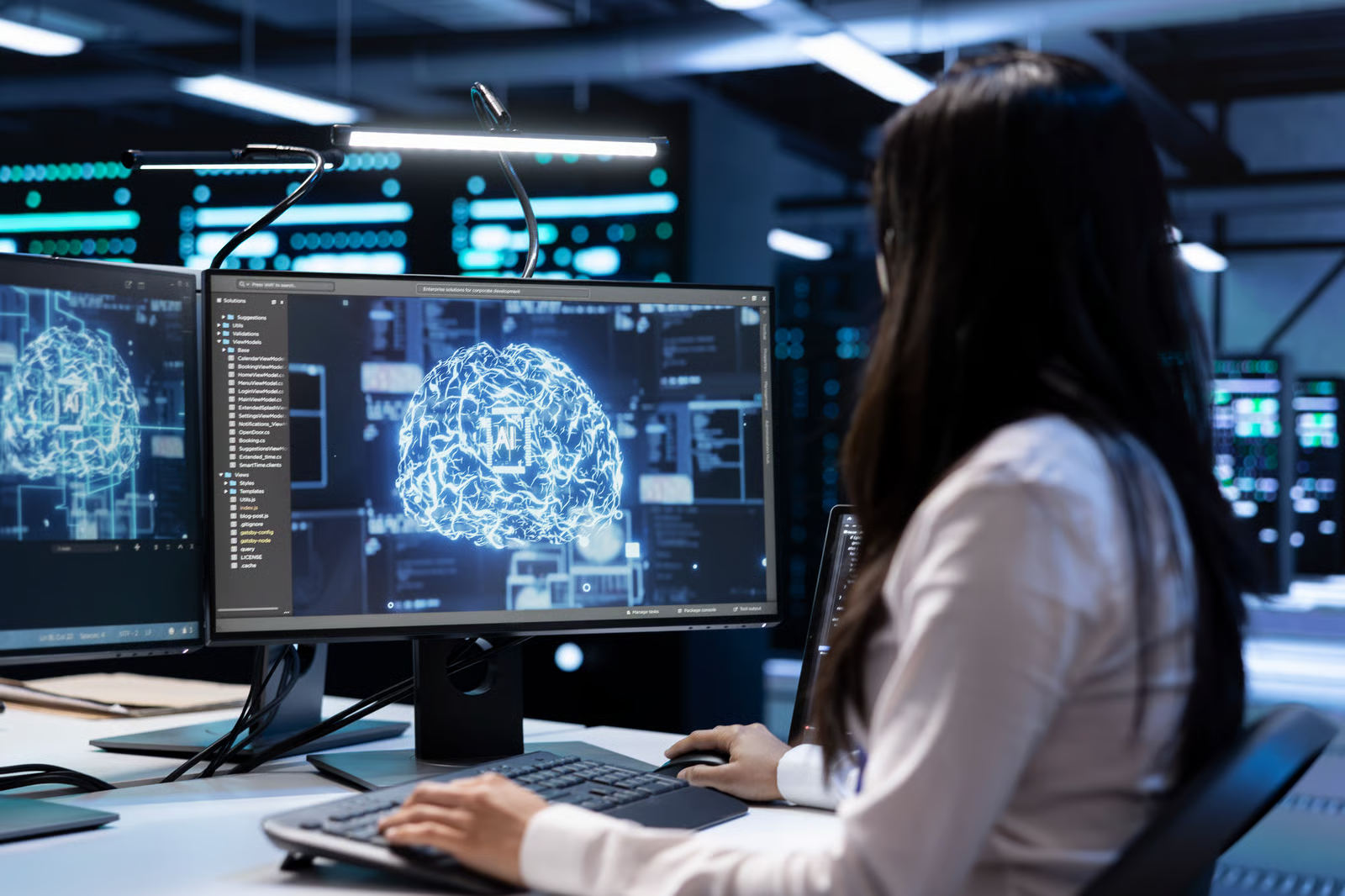 Engineer monitors enterprise AI systems and model performance on multiple screens in a data center environment.