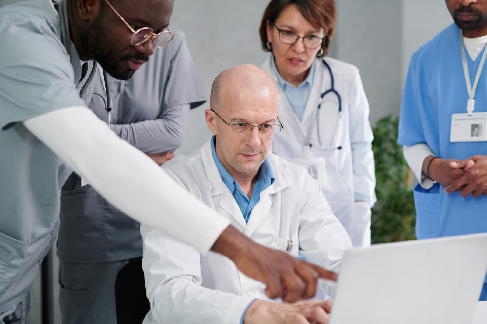 Healthcare professionals collaborating around a laptop to review clinical information and support healthcare software decision-making.