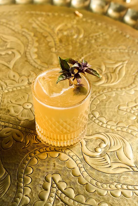 Drink autoral servido sobre bandeja de latão
