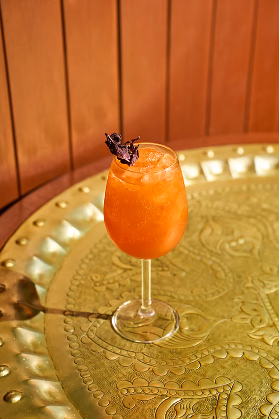 Drink de hibisco em taça sobre bandeja dourada