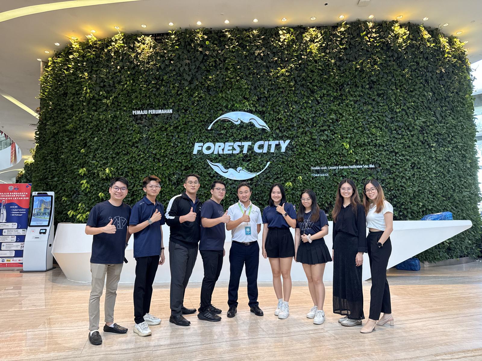 Apricity team in front of the Forest City green wall