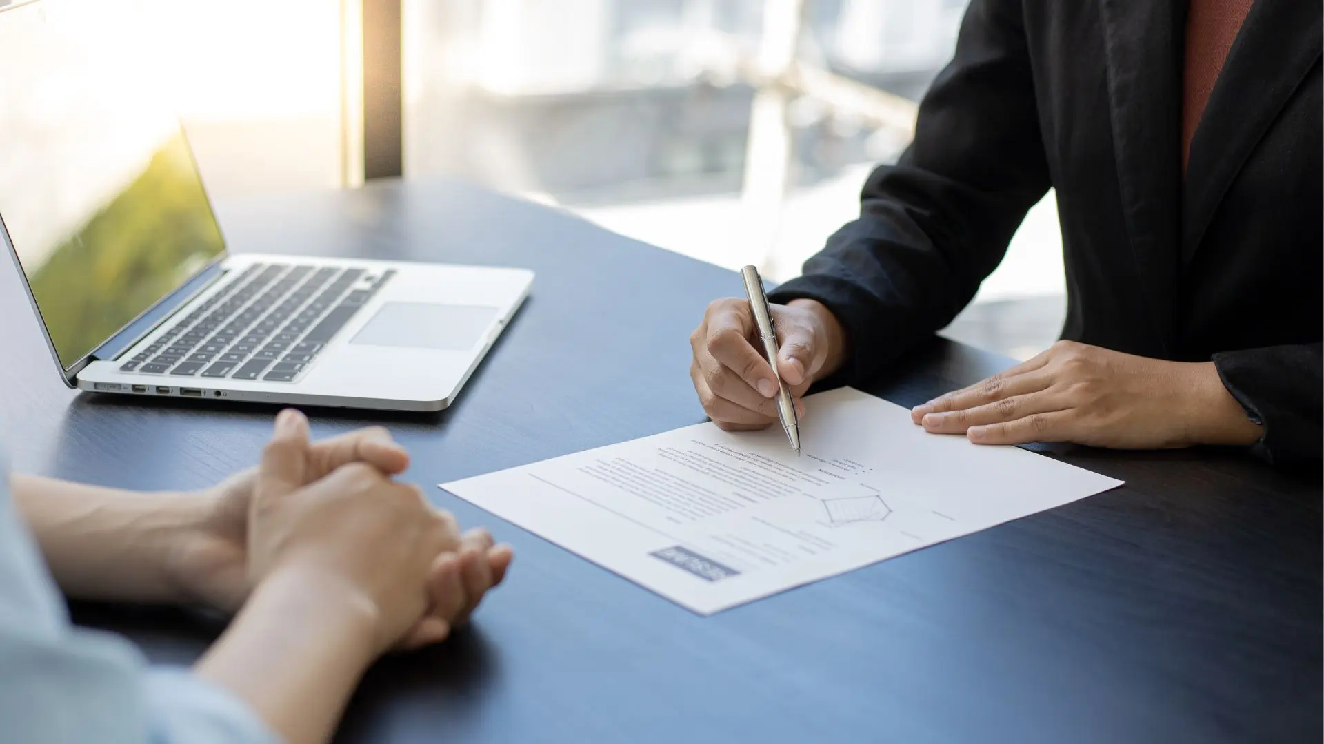 Executive reviewing requirement profiles and candidate documents at a desk during a personnel interview.