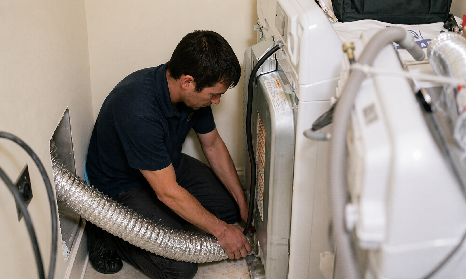Technician cleaning a clogged dryer vent duct