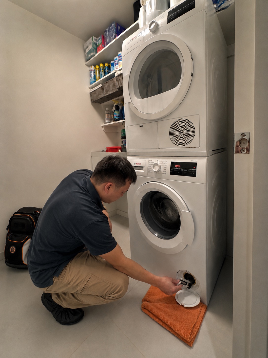 GOAS technician repairing a stacked Bosch washer and dryer in a NYC apartment
