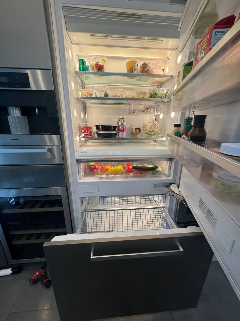 Miele kitchen wall in a NYC apartment during service: built-in refrigerator with door open, wine cooler and built-in coffee machine