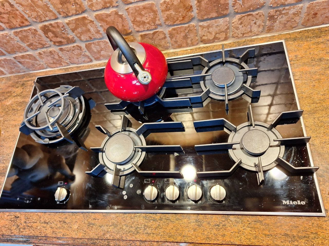 Black glass Miele gas cooktop with five burners in a NYC kitchen