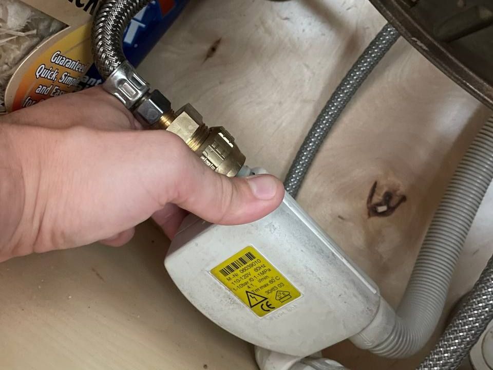 Technician holding a Miele dishwasher water intake valve during repair